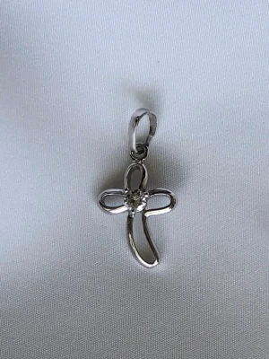 Korshänge silver - Sött korsformat hänge i silverfärgad metall. Hänget har en snirklig design och en liten glittrande sten i mitten. Materialet är okänt men kvaliteten är hög. Metallen glänser lika fint som när det köptes och är inte sliten nånstans.