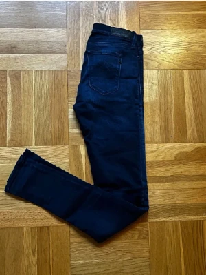 Mörkblå skinny jeans från Replay - Snygga mörkblå skinny jeans från Replay med klassisk femficksdesign och smal passform. Jeansen har en lätt tvättad look och är tillverkade i stretchigt material för extra komfort. Perfekta för en trendig och avslappnad stil.