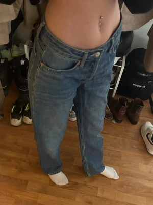 Low waist blå raka jeans från Lager 157 - Säljer ett par klassiska blå jeans med rak passform och hög midja. Jeansen har fem fickor, knappgylf och är tillverkade i ett robust denimtyg. Perfekta för en avslappnad och trendig look. 