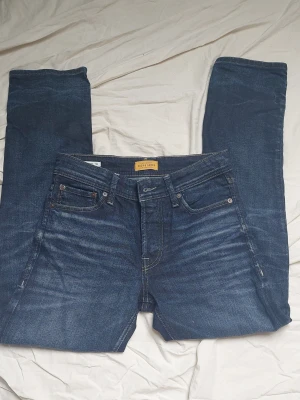 Jack & Jones slim fit - Snygga mörkblå jeans från Jack & Jones med klassisk femficksdesign och subtila slitningar framtill. Jeansen har raka ben och är tillverkade i bomullsdenim med en liten mängd stretch för extra komfort. Perfekta för en avslappnad och trendig look.