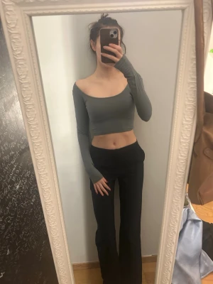 Grå/grön offshoulder croppad topp - Säljer en stilren grå croppad topp med offshoulder-design och långa ärmar. Perfekt för dig som gillar en slim och modern look. Materialet känns mjukt och stretchigt, vilket gör den bekväm att bära. Passar till både jeans och kjol.