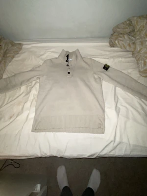 Beige stickad henley från Stone Island - Säljer en beige stickad henley från Stone Island med klassisk patch på ärmen. Tröjan har ribbade muddar, lång ärm och knappar vid halsen samt en dragkedja. Perfekt för dig som gillar stilrena och exklusiva plagg. Denna stickade stone Island tröjan är också äkta. Den passar i S och M.  Har du frågor så kan du skriva!! Tack i förväg 
