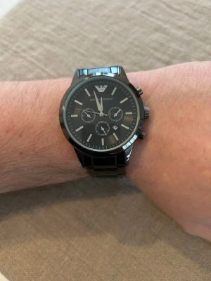 Herrklocka Chronograph E.A 43mm - Stilren svart klocka från Emporio Armani med armband i stål  och klassisk urtavla. Klockan har flera små urtavlor och tydliga indexmarkeringar. Absolut nyskick enligt bilder. Perfekt accessoar för dig som gillar en clean och modern look. Replika AAA. Fungerar men behöver nytt batteri.