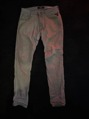 Replay anbass slim fit - Säljer ett par ljusgrå slim fit jeans från Replay med klassisk femficksdesign och dragkedjegylf. Jeansen har raka ben och diskreta sömmar, perfekta för en avslappnad men ändå stilren look. Materialet är mjukt och följsamt för extra komfort.
