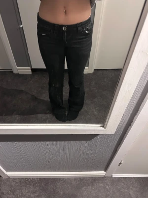 Svarta bootcut jeans med fickdetaljer - Säljer ett par svarta bootcut jeans med snygga fickdetaljer och vita sömmar. Jeansen har låg midja och klassisk femficksmodell. Passar perfekt till en trendig och avslappnad stil. Storlek 152 barnstorlek, gick inte att skriva in det i storlek med den riktiga storleken är 152 i barnstorlek. Org pris ca 400kr