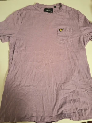 Ljuslila t-shirt från Lyle & Scott - Snygg ljuslila t-shirt från Lyle & Scott med klassisk rund hals och bröstficka med den ikoniska gula loggan. Perfekt basic-plagg i mjuk bomull som passar till det mesta.