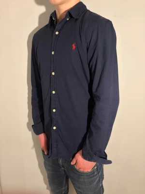 Mörkblå skjorta från Ralph Lauren - Strl S - Ralph Lauren skjorta 👔✨ Mörkblå och stilren 💙 Storlek S 👀 I fint skick och väl omhändertagen 🔥 Nypris runt 1 400 kr 💸 – vårt pris 399 kr 🔥 Snygg passform som funkar både uppklätt och mer avslappnat 😎 Klassisk och tidlös design Modellen på bild är ca 176 cm och väger runt 63 kg Kolla in profilen för flera skjortor 👀✨ Hör av er om ni har frågor eller vill ha fler bilder 💬