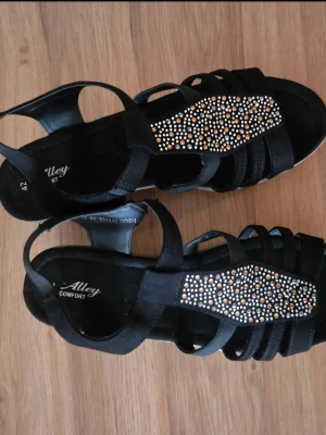 Svarta sandaler med strassdetaljer - Snygga sandaler från Alley med flera remmar och glittrande strassdetaljer framtill. Perfekta till sommaren.