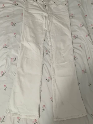 Vita bootcut jeans med brodyr - Säljer ett par vita bootcut jeans med snygg broderad detalj på bakfickorna. Jag har använt dessa jeans 1-2 gånger eftersom att de inte passar min stil längre. Ifall du har några frågor så är det bara att fråga på❤️De är storleken S med full length, perfekt för långa tjejer!! själv är jag 175cm och de är den perfekta längden.
