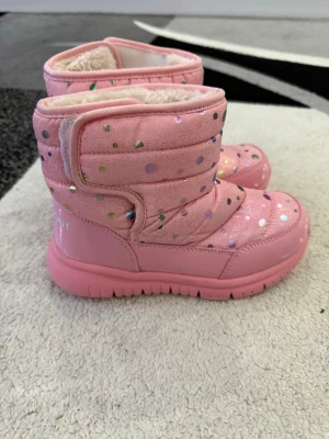 Rosa vinterkängor med glitterprickar - Säljer ett par rosa vinterkängor med glansiga, färgglada glitterprickar och mjukt, vitt foder. 
