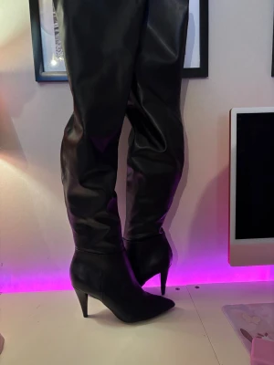 Svarta höga boots med klack - Säljer ett par svarta höga stövlar med spetsig tå och smal klack. Stövlarna har dragkedja på insidan och är gjorda läder material, använd 2ggr endast 1gång ute.
