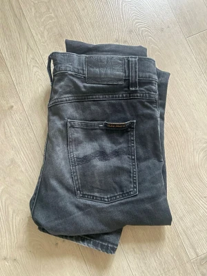 Svarta slim fit jeans från Nudie Jeans - Säljer ett par svarta slim fit jeans från Nudie Jeans med klassisk femficksmodell och diskret logga på bakfickan.  Lean Dean 30/32