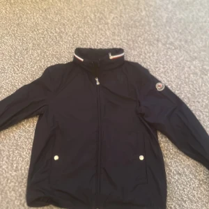 Svart jacka  från Moncler - Svart jacka från Moncler med hög krage och dragkedja. Jackan är i mycket fint skick, man scanna koden i jackan. 