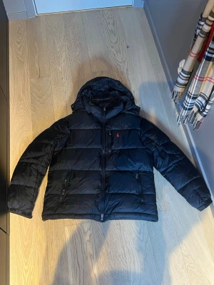 Polo Ralph lauren puffer jacket  - Säljer en Ralph Lauren puffer jacket i svart, i helt nyskick. Jackan är endast använd cirka 4 gånger och har inga skador, fläckar eller slitage. Prislappen är borttagen men jackan är i princip som ny.  Storlek M, men passar även dig som normalt har storlek S då den sitter bra och inte känns för stor.  Anledningen till försäljning är att jag har köpt en MooseKnuckles jacka istället, och denna blev tyvärr inte riktigt min stil.  En stilren och varm jacka av hög kvalitet. Hör gärna av er vid frågor