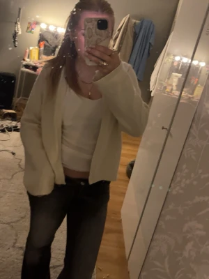 Krämvit kofta med öppen front - Mysig krämvit kofta med öppen front och långa ärmar. Koftan är i ett mjukt material och har en avslappnad passform.