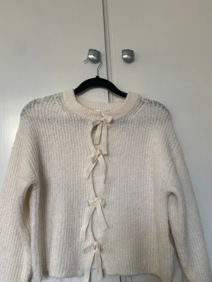 Stickad tröja - Säljer en krämvit stickad tröja från Gina Tricot med fyra gulliga rosetter framtill. Skriv och fråga om ni undrar nått💕💕