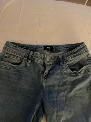 Blå jeans från LTB Valerie - Ett par klassiska blå jeans från LTB, modell Valerie. Jeansen har fem fickor, låg midja och raka ben. Tillverkade i ett mjukt denimtyg med snygg tvätt och kontrastsömmar. Perfekta för en avslappnad och trendig look.