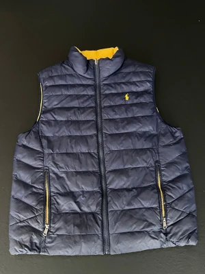 Ralph Lauren dubbelsidig väst  - En riktigt schysst dubbelsidig väst ifrån Ralph Lauren! Kvaliten är rätt bra och storleken är XL i barnstorlek! Vilket motsvarar ca S eller XS i herrstorlek! Den är rätt använd, tveka inte på att skriva om du är i behov av fler bilder!📸 Skriv gärna om du har minsta lilla fundering då jag oftast svarar direkt!🖋️ Fraktar alltid senast dagen efter! 📦