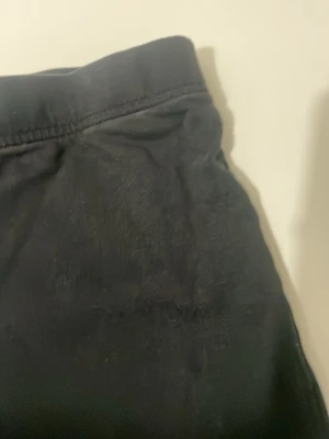 Svarta leggings med hög midja - Svarta leggings med hög midja och stretchigt material som sitter tajt längs benen. Perfekta för en avslappnad och stilren look. Klassisk design utan synliga detaljer eller loggor.