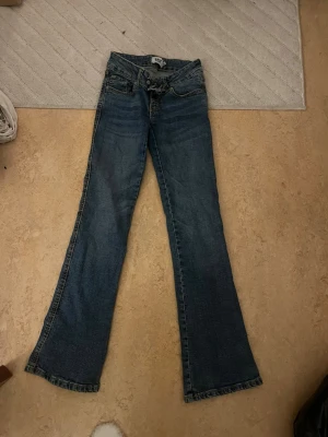 Blå bootcut jeans från 157 - Säljer dessa jättefina bootcut jeans från lager 157. Har en bra passform och formar kroppen bra. De har gått sönder lite där man knäpper byxorna. Men när man knäpper så syns det inte vilket jag visar på en bild längre fram. De är använda två gånger. Passar mig som brukar ha xs.💕💕