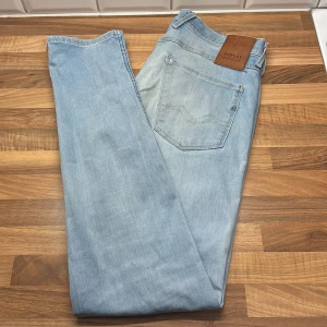 Replay Anbass ljusblå jeans - Säljer ett par Replay Anbass Hyperflex jeans i ljusblå tvätt. Klassisk femficksmodell med snygga detaljer och skinnpatch bak. Jeansen är tillverkade i stretchigt denim för extra komfort och har en modern passform som sitter riktigt bra.