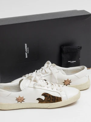 Saint Laurent vita sneakers med stjärnor - Unika vita sneakers från Saint Laurent med bruna och svarta detaljer i form av stjärnor och vågor på sidorna. Skorna har klassisk snörning, beige sula och är tillverkade i läder med inslag av mocka. Perfekta för dig som vill sticka ut med en cool och exklusiv look.