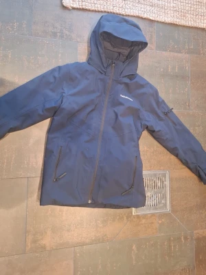 Peak Performance jacka i mörkblå färg. - Peak Performance jacka i mörkblå färg. I nyskick, knappt använd och helt utan slitage. Vind- och vattenavvisande med huva och flera praktiska fickor. Perfekt för vardag, höst/vinter och utomhusbruk. Och köpte för 2100 Skriv vid frågor😁