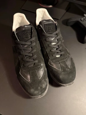 Svarta Maison Margielas storlek 42 - Ett par riktigt feta svarta på svarta Maison Margiela Replica Gats I storlek 42. Riktigt trendiga skor. Till skorna ingår det dustbag. Tyvärr ingen kartong. Hör av dig vid frågor eller om du vill ha fler bilder!