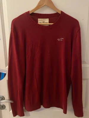 Vinröd stickad tröja från Hollister - Snygg vinröd stickad tröja från Hollister med rund   Enkel och stilren design Priset är inte hugget i sten!🪨 