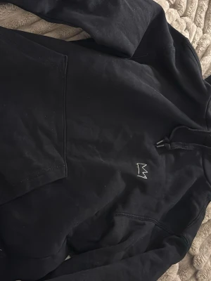 Svart Hov1 hoodie med turnétryck - Säljer en svart hoodie från Hov1 med broderad krona på bröstet och stort turnétryck på ryggen med texten 'Vi Dansar Vidare I Livet' och turnédatum. Hoodien har huva med dragsko och stor magficka. Perfekt för dig som gillar svensk hiphop och vill ha något unikt från turnén.