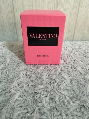 Valentino Donna Born In Roma EdP 100ml - Valentino Donna Born In Roma är en lyxig parfym i en elegant, fyrkantig glasflaska med nitar och svart lock. Doften kommer i en snygg rosa kartong med svart etikett. Flaskan rymmer 100 ml och utstrålar exklusivitet och modern stil.