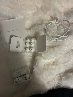 Apple AirPods Pro med laddningsetui - Säljer ett par vita Apple AirPods Pro med trådlöst laddningsetui. Inkluderar extra silikonpluggar i olika storlekar och laddningskabel. Snygg och kompakt design i blankt plastmaterial, perfekt för dig som vill ha grymt ljud och smidig anslutning till din iPhone.1:1