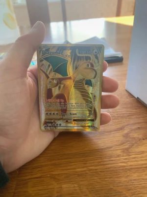 Dragonite EX Pokémonkort holografiskt - Säljer ett Dragonite EX Pokémonkort med holografisk yta och guldfärgad design. Kortet har 180 HP och visar Dragonite med gröna vingar och guldskimrande bakgrund. Perfekt för samlare eller Pokémonfans.