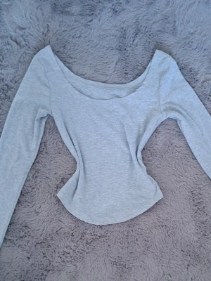 Ljusgrå och beige långärmade toppar med båtringning - Säljer två stilrena långärmade toppar med bred båtringning. Topparna har en figurnära passform och är tillverkade i mjuk bomullsmix som känns skön mot huden. Perfekt att matcha med jeans eller kjol för en clean look.