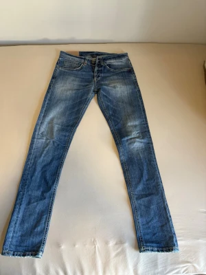 Blå slim fit jeans med slitningar - Snygga blå slim fit jeans med lätt slitna detaljer och klassisk femficksdesign. Jeansen har en något tvättad look och raka ben. Perfekta för en avslappnad och trendig stil. Tvättlappen är borttagen men jeansen är slim fit och har lite stretch. 