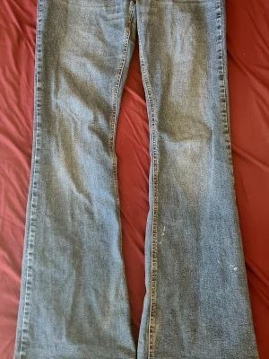 Blå bootcut jeans - Ett par klassiska blå bootcut jeans med utsvängda ben och normal midja. Jeansen har en tidlös tvätt och är tillverkade i denim, perfekt för dig som gillar en retrostil. Passar till många olika outfits och ger en avslappnad vibe.