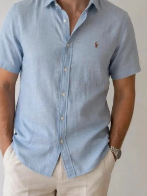 Ljusblå kortärmad skjorta från Polo Ralph Lauren - Snygg ljusblå skjorta från Polo Ralph Lauren med korta ärmar och klassisk krage. Superfin och använd endast någon gång. Nypris ca 1400kr!