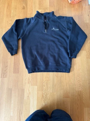 Vintage Svart quarter-zip sweatshirt - Vintage Mörkblå sweatshirt med halv dragkedja och hög krage från NYSCAN. Tröjan har långa ärmar, muddar vid ärmslut och nederkant samt broderad logga på bröstet. Perfekt för en chill och stilren look. Finns 1 litet hål på armen samt en liten fläck på den andra