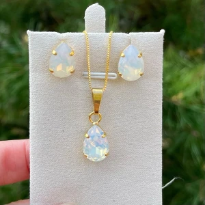Smyckesset örhängen halsband Pear White Opal - Ett set med halsband och stud örhängen. Guldplätterad mässing och kristaller. Pear 14mm, färg White Opal. Längd 48cm inkl lås och förlängningskedja.  Finns även att få i andra färger på kristallen.  Jag skickar endast spårbart, samfraktar. Fast pris. Besök gärna mina övriga annonser.  Till mina smycken använder jag kristaller från Preciosa, Aurora och Swarowski.