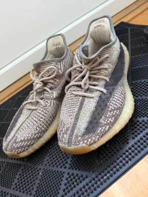 Yeezy Boost 350 V2 i beige och brunt - Säljer ett par Yeezy Boost 350 V2 med stickad ovandel i beige och bruna toner, väldigt bra skick. Inkl box och kvitto