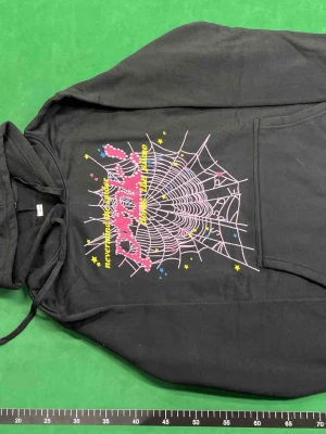 Svart loungewear-set med tryck - Coolt svart loungewear-set med hoodie och byxor. Båda delarna har färgglada tryck med texten 'prank!' och 'never mind the spider, heres the slime', samt stjärnor och spindelnät i rosa, gult och blått. Perfekt för chill dagar hemma.