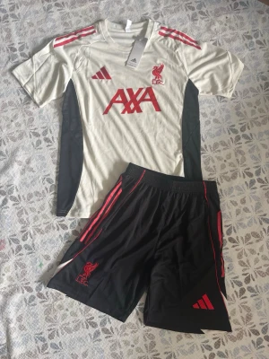 Liverpool träningsset från Adidas - Liverpool fotbollsträningsset i storlek S. Shortsen har fickor med dragkedjor. Helt nya och oanvända, perfekt till sommaren. Hör gärna av vid frågor!