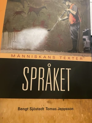 Oanvänd Människans texter Språket - Kursbok i svenska, 'Människans texter Språket', med svart och orange omslag. Boken har ett konstnärligt motiv på framsidan och är skriven av Bengt Sjöstedt och Tomas Jeppsson. Perfekt för gymnasiet eller högskolestudier inom språk.