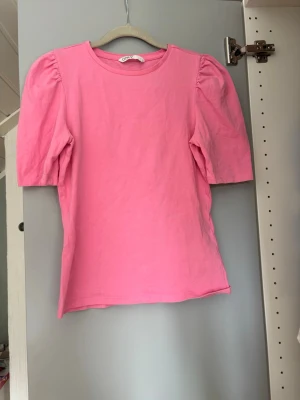 Rosa puffärm t-shirt från Only - Säljer en rosa t-shirt från Only med puffärmar och rund halsringning. T-shirten har en enkel och clean design med lite längre korta ärmar som ger en trendig siluett. Tillverkad i mjuk bomull för skön känsla. En liten fläck se bild 4, men den går säkert bort med fläckbortagninf