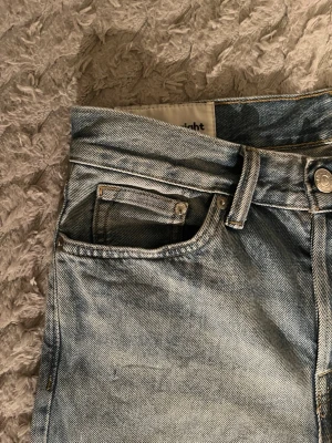 Original straight jeans från H&M - Säljer ett par ljusblå jeans från H&M i modellen Original straight med regular fit. Klassisk femficksdesign och raka ben. Jeansen är i denim och har snygga slitningar för en avslappnad look.