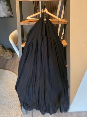 Svart långklänning med öppen rygg från H&M - Säljer en svart långklänning med öppen rygg och tunna axelband. Klänningen har en luftig och flowy passform, perfekt för dig som gillar en avslappnad och stilren look. 