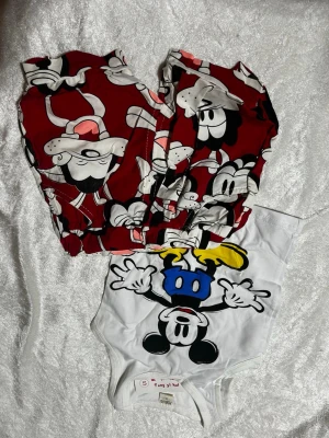 Musse Pigg pyjamas-set - Sött pyjamas-set med Musse Pigg-tryck. Byxorna är vinröda med stora Musse Pigg-motiv och toppen är vit med en färgglad Musse Pigg-illustration. Perfekt för dig som älskar Disney och vill ha något bekvämt att chilla i. Stlk 92-98 