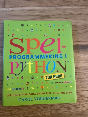Spelprogrammering i Python för barn - Färgglad bok om spelprogrammering i Python, riktad till barn. Boken har ett grönt omslag med lekfulla illustrationer och tydliga instruktioner för att lära sig bygga egna datorspel steg för steg. Perfekt för unga som vill lära sig programmering på ett enkelt och roligt sätt.