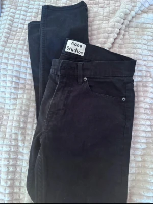 Svarta Acne Studios jeans Ace Stay Cash - Säljer ett par svarta jeans från Acne Studios, modell Ace Stay Cash. Jeansen är raka i modellen och har klassisk femficksdesign. Tillverkade i 100% bomull för en skön och slitstark känsla. Perfekta för dig som gillar stilrena och tidlösa plagg.