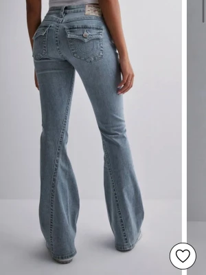 True Religion ljusblå bootcut jeans - Säljer ett par ljusblå bootcut jeans från True Religion med ikoniska fickor bak och snygga kontrastsömmar. Jeansen har låg midja och klassisk knappdetalj på fickorna. Storlek 29, erbjuder rabatt om flera par byxor köps vid intresse